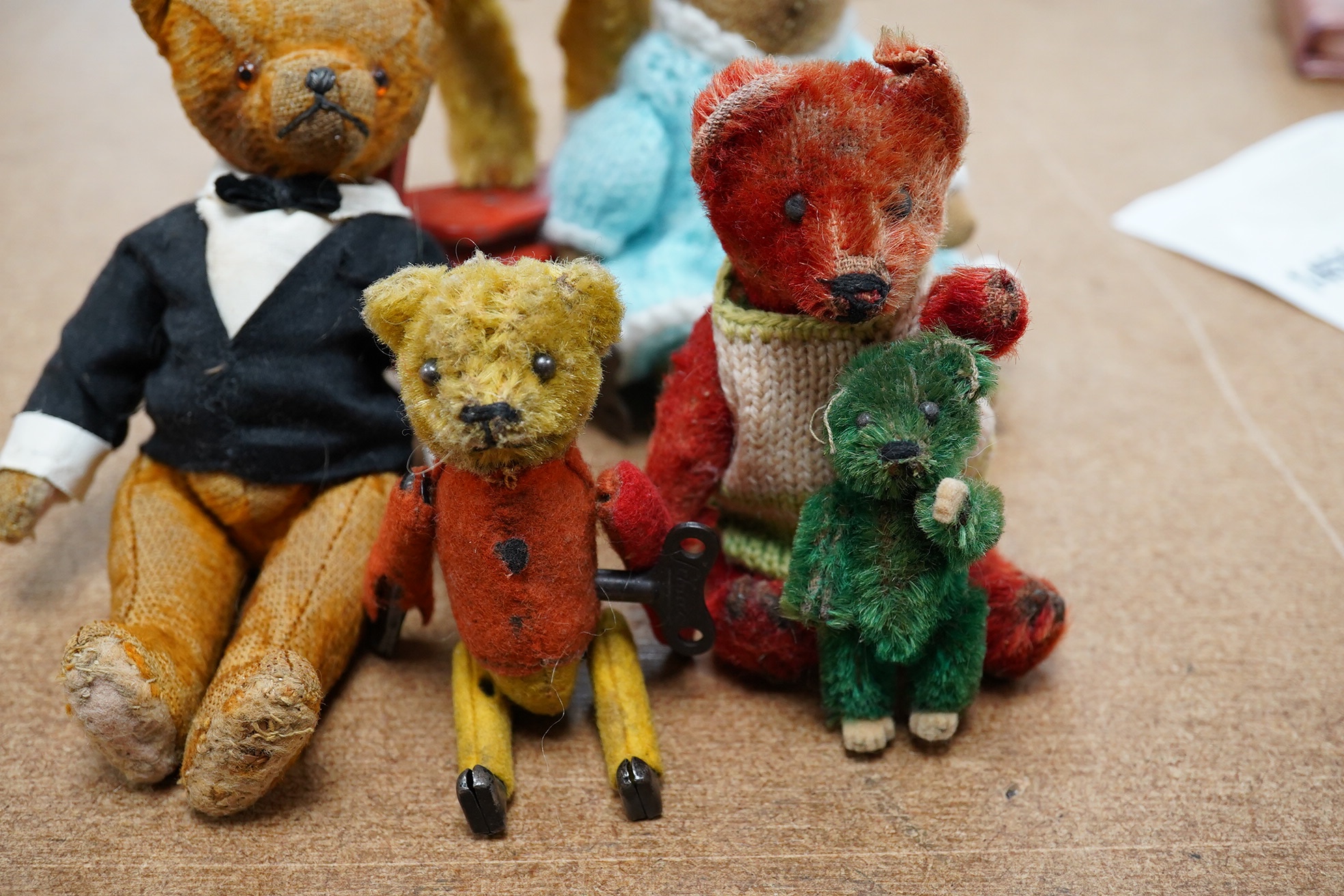 A mechanical bear on a bike in good working condition, a red Schuco bear, faded condition, c.1920, 13cm, a tumbling Schuco bear, working, 10cm, c.1920, a green Schuco bear missing one ear, c.1920, 7cm. high, together wit